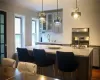 Kitchen featuring dark hardwood / wood-style floors, a kitchen island with sink, a kitchen bar, tasteful backsplash, and wall chimney exhaust hood