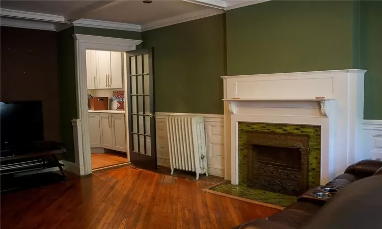 Living room featuring radiator, hardwood / wood-style floors, and crown molding