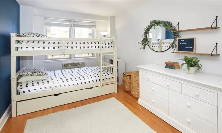 Bedroom featuring light hardwood / wood-style floors and an AC wall unit