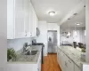 Kitchen with hanging light fixtures, white cabinets, sink, light hardwood / wood-style floors, and appliances with stainless steel finishes