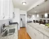 Kitchen featuring stainless steel appliances, hanging light fixtures, white cabinets, sink, and light hardwood / wood-style flooring