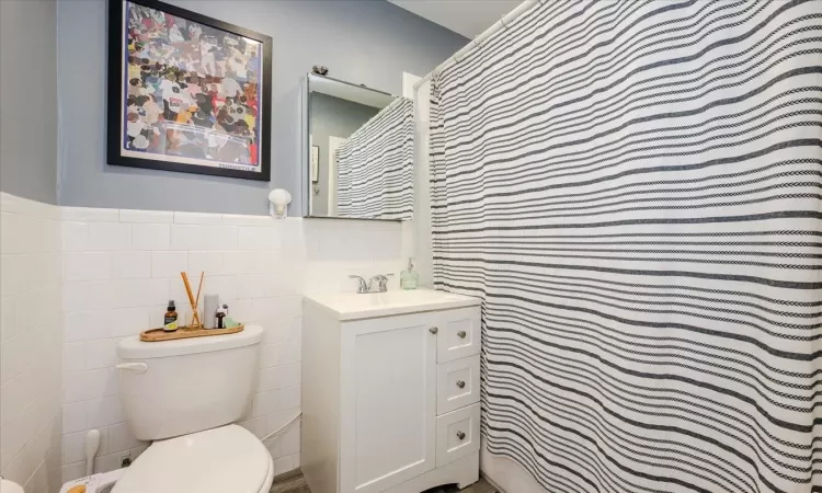 Bathroom with vanity, tile walls, and toilet