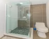 Bathroom featuring toilet, tile walls, and a shower with shower door