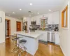 Kitchen featuring light stone countertops, light wood-type flooring, stainless steel appliances, white cabinets, and a kitchen island