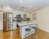 Kitchen with light hardwood / wood-style floors, a center island, white cabinetry, and appliances with stainless steel finishes