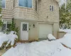 Snow covered property entrance with a garage