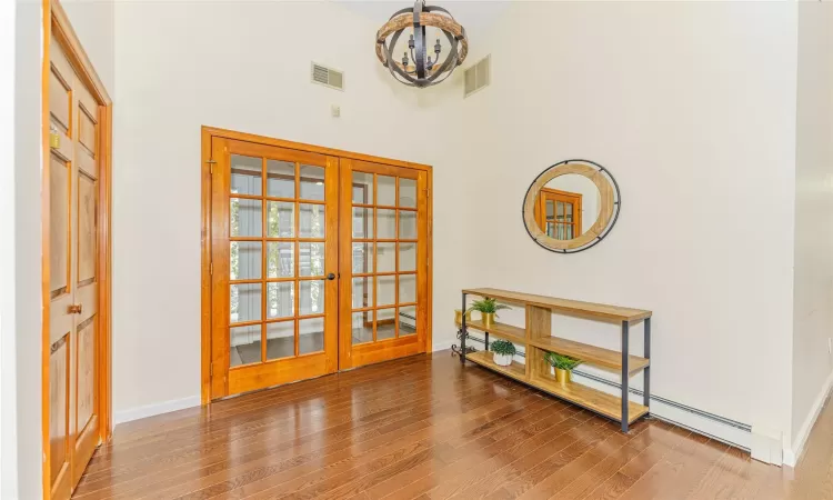 Doorway to outside featuring hardwood / wood-style flooring, a chandelier, a towering ceiling, and french doors