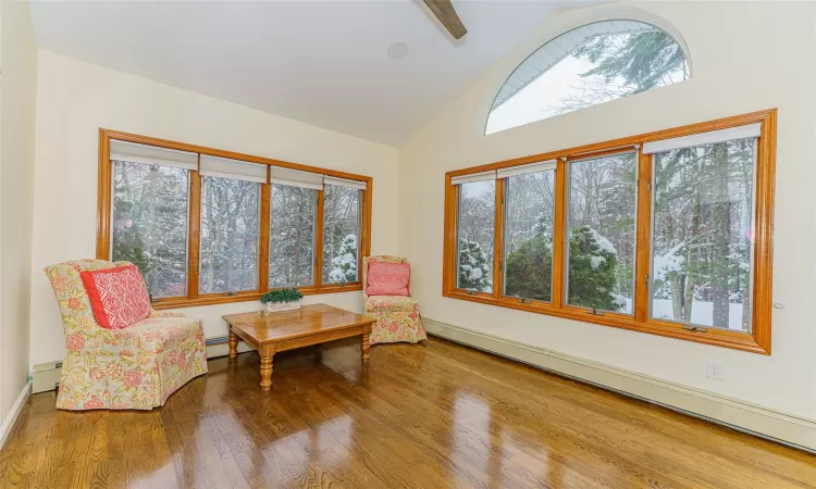 Living area with baseboard heating, high vaulted ceiling, and hardwood / wood-style flooring