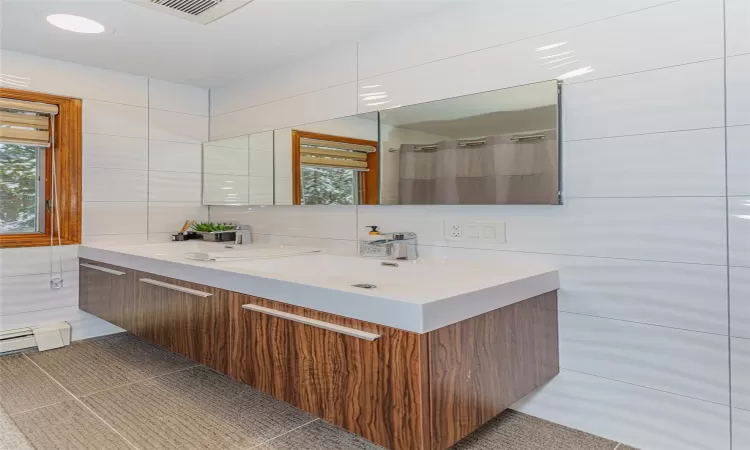 Bathroom featuring vanity, tile patterned flooring, decorative backsplash, tile walls, and a baseboard radiator