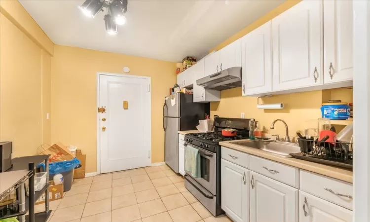 Kitchen featuring ceiling fan, light tile patterned flooring, white cabinetry, and stainless steel appliances