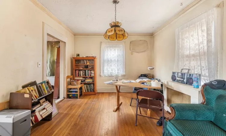 Living room featuring ceiling fan, light hardwood / wood-style floors, ornamental molding, and a brick fireplace