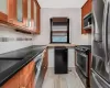 Kitchen featuring appliances with stainless steel finishes, light wood-type flooring, and dark stone counters