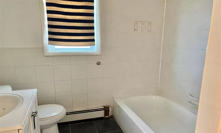 Bathroom featuring vanity, a baseboard heating unit, tile patterned floors, a washtub, and tile walls