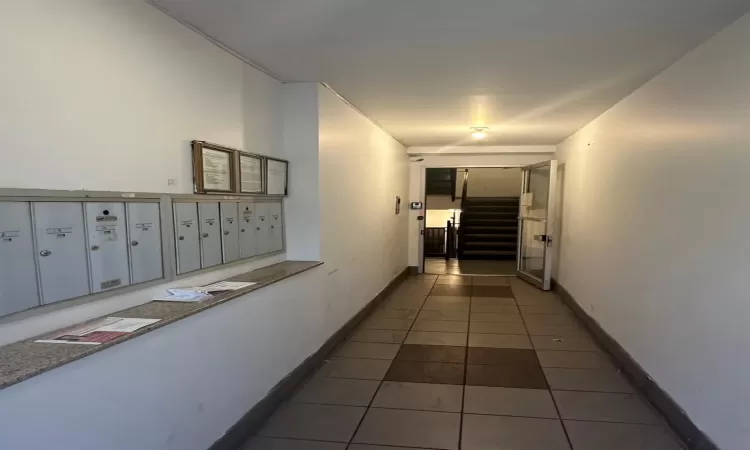 Corridor featuring dark tile patterned flooring and a mail area