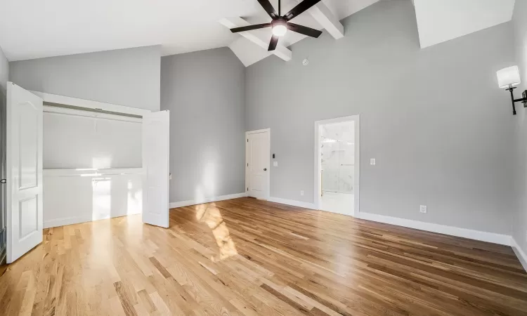 Unfurnished living room featuring hardwood / wood-style flooring, ceiling fan, and high vaulted ceiling