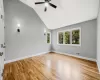 Empty room featuring light wood-type flooring, plenty of natural light, lofted ceiling, and ceiling fan