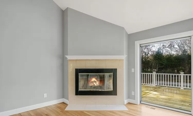 Unfurnished living room with a fireplace, lofted ceiling, and hardwood / wood-style flooring