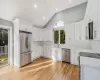 Kitchen with tasteful backsplash, white cabinetry, light wood-type flooring, and appliances with stainless steel finishes