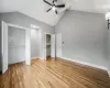 Unfurnished bedroom featuring ceiling fan, lofted ceiling, and light hardwood / wood-style flooring