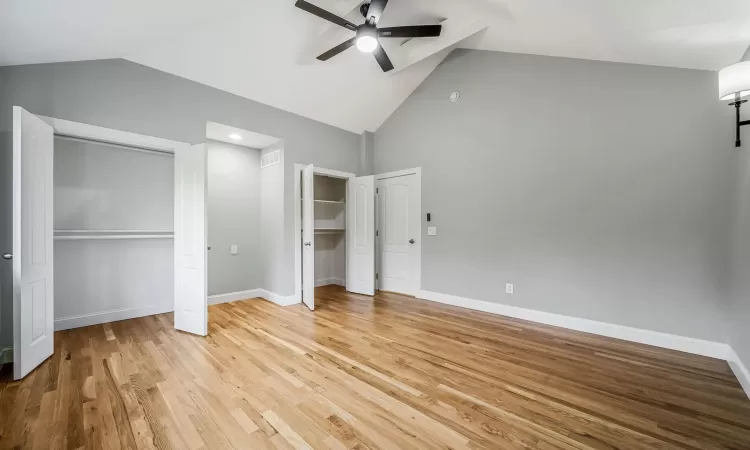 Unfurnished bedroom featuring ceiling fan, lofted ceiling, and light hardwood / wood-style flooring