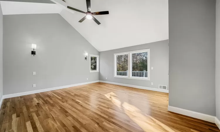 Unfurnished living room featuring light wood-type flooring, high vaulted ceiling, and ceiling fan