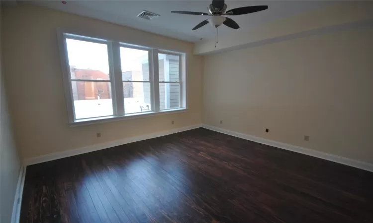 Empty room with dark hardwood / wood-style flooring and ceiling fan