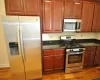 Kitchen with wood-type flooring, stainless steel appliances, and dark stone counters