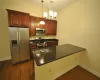 Kitchen with sink, hanging light fixtures, dark hardwood / wood-style floors, dark stone countertops, and appliances with stainless steel finishes