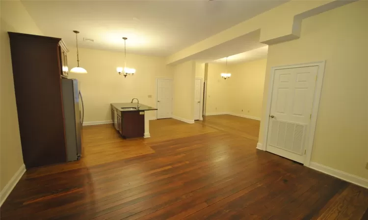 Unfurnished room with sink, dark wood-type flooring, and an inviting chandelier