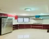 Kitchen with stainless steel refrigerator, sink, white gas stovetop, extractor fan, and light tile patterned floors