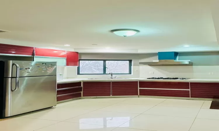 Kitchen with stainless steel refrigerator, sink, white gas stovetop, extractor fan, and light tile patterned floors