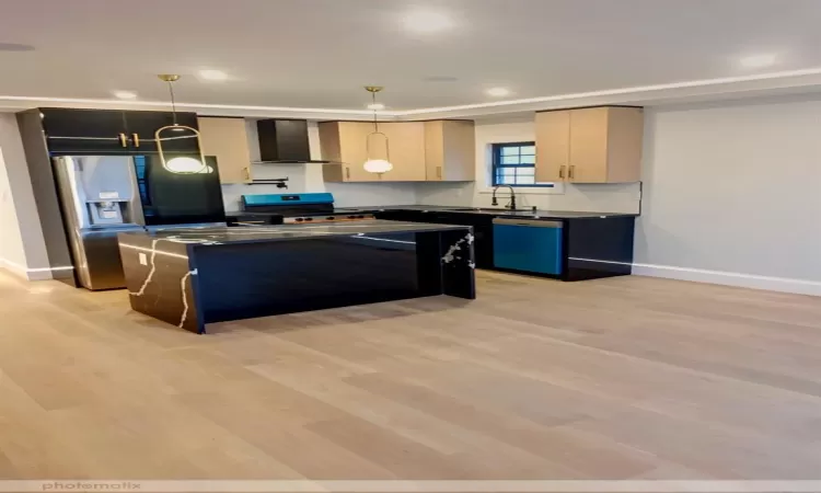 Kitchen with pendant lighting, a center island, wall chimney range hood, light brown cabinetry, and dishwashing machine