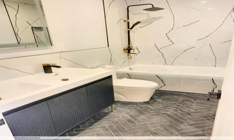 Full bathroom featuring vanity, toilet, tiled shower / bath, and tile walls