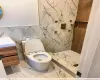 Bathroom with a shower, vanity, toilet, and tile walls