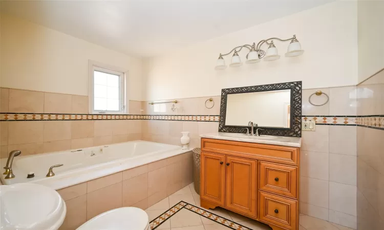 Bathroom featuring tile patterned flooring, vanity, tile walls, and toilet