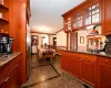 Kitchen featuring an inviting chandelier, stainless steel refrigerator with ice dispenser, crown molding, dark stone counters, and pendant lighting