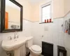 Bathroom featuring heating unit, toilet, tile walls, and sink