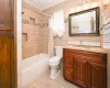 Full bathroom with vanity, shower / bath combination with curtain, crown molding, toilet, and tile walls