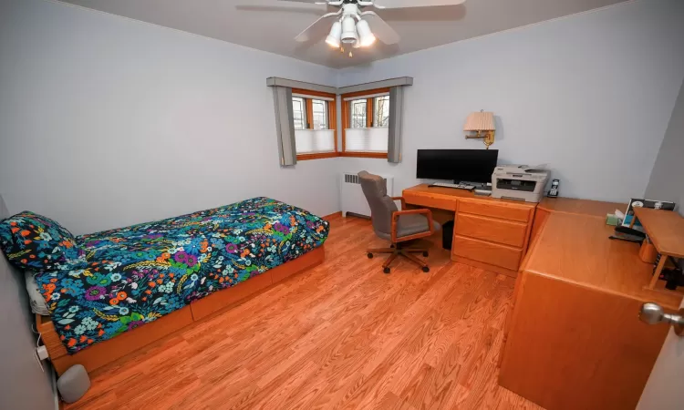 Bedroom with ceiling fan, radiator, and light hardwood / wood-style flooring