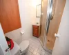 Bathroom featuring tile patterned floors, vanity, tile walls, toilet, and a shower with shower door