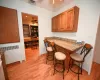 Kitchen with a breakfast bar, radiator, ceiling fan, light hardwood / wood-style floors, and light stone counters