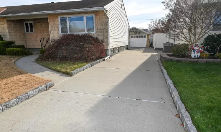 View of side of home featuring a lawn, a garage, and an outdoor structure