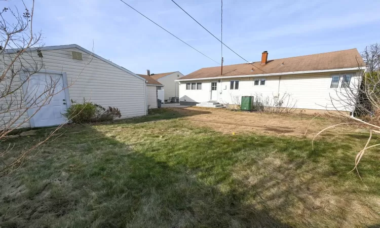 Back of house featuring a lawn and central AC