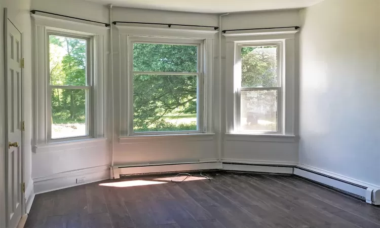 Full bathroom with radiator heating unit, shower / bathtub combination with curtain, tile patterned flooring, toilet, and tile walls