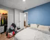 Bedroom with a paneled ceiling, a walk in closet, wood-type flooring, and a closet