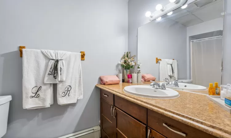 Bathroom featuring a shower with shower curtain, vanity, and toilet