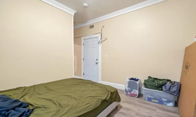 Bedroom with wood-type flooring and ornamental molding