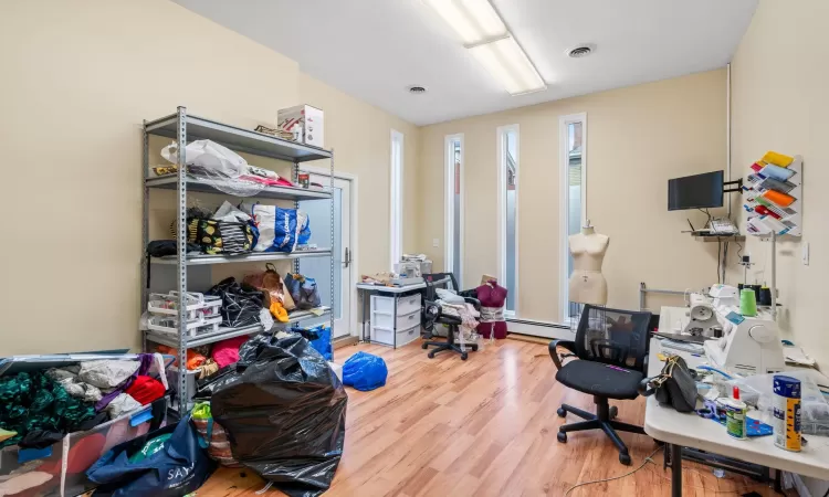 Office area with hardwood / wood-style flooring and a baseboard heating unit