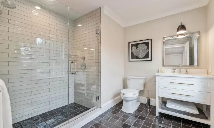 Bathroom featuring tile patterned floors, crown molding, an enclosed shower, toilet, and vanity