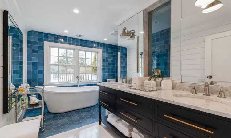 Bathroom with tile patterned floors, vanity, a bath, and tile walls